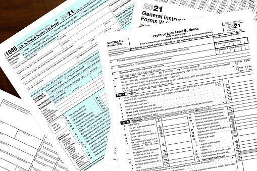 Various 2021 IRS tax forms on a wood desktop.